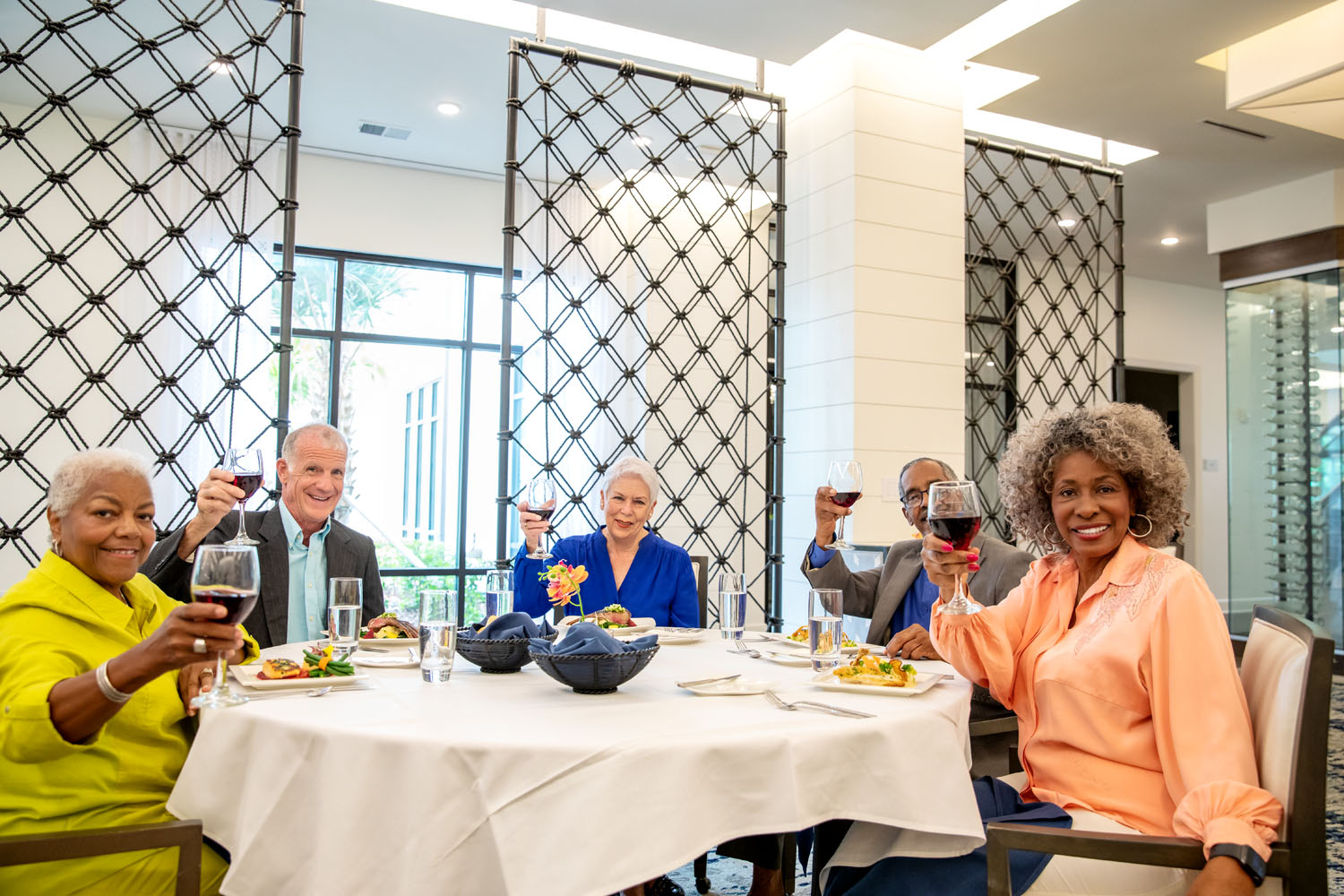 arbor terrace residents smiling and holding wine glasses