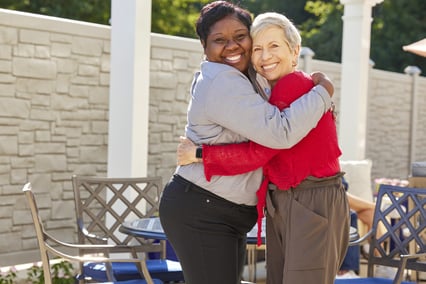 Senior and employee hugging on the patio