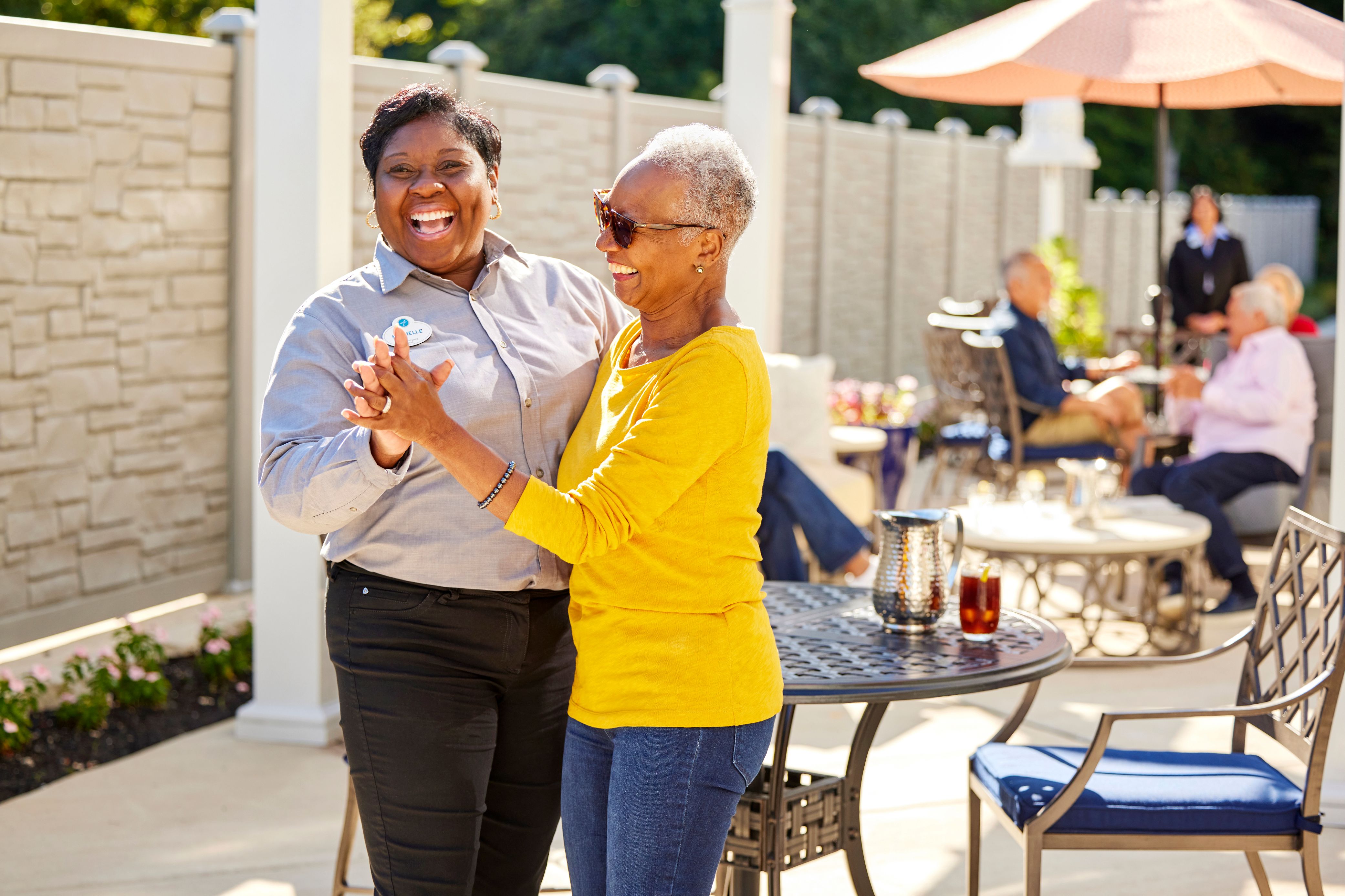 Arbor terrace employee smiling dancing with resident on patio